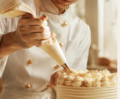 Chef piping cream onto a celebration cake